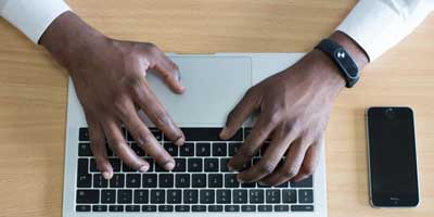 black hands typing at a laptop