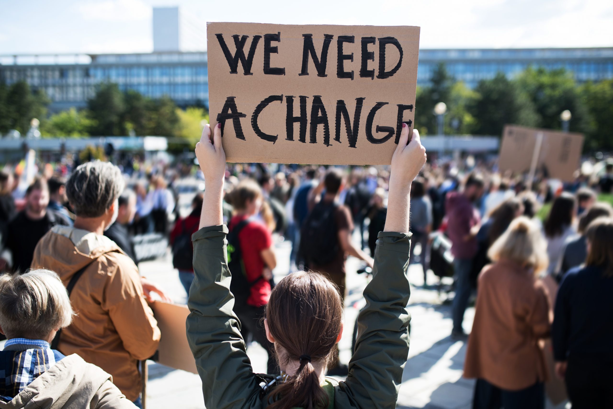 "We Need A Change" sign at a large protest