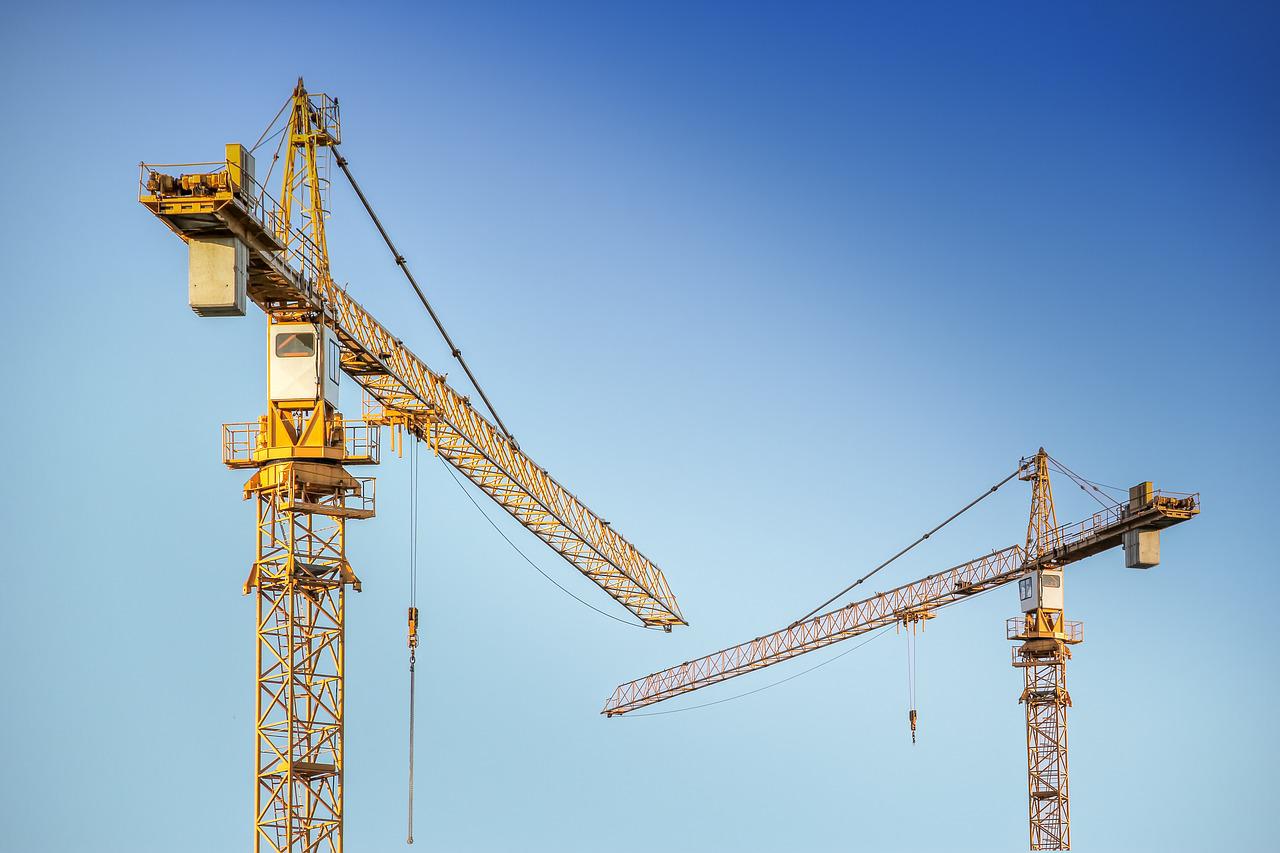 The tops of two cranes with the blue sky in the background