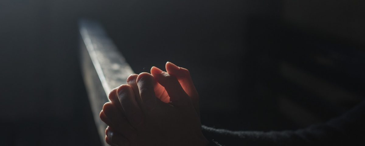 Hands being illuminated by light on a pew