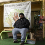 Lavain Henderson, a youth mentor with Youth United for Community Action (YUCA), sits outside the organization’s office in East Palo Alto on Dec. 11, 2025. Henderson, who previously experienced homelessness, works with young people as YUCA faces uncertainty tied to federal cuts to permanent supportive housing funding.
