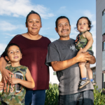 Two adults with two kids in between permanent supportive housing buildings