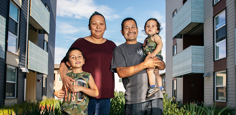 Two adults with two kids in between permanent supportive housing buildings