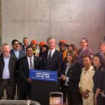 Governor Newsom at podium surrounded by other elected officials and advocates
