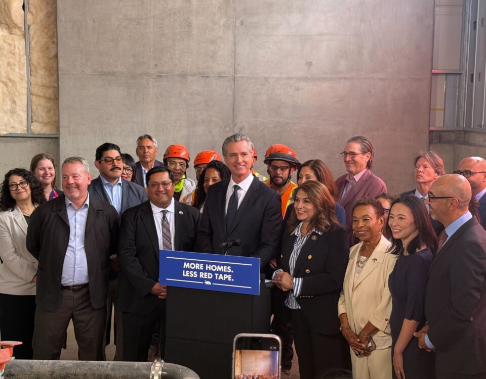 Governor Newsom at podium surrounded by other elected officials and advocates